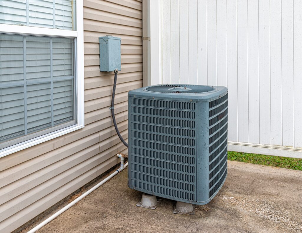 Horizontal shot of an air conditioning unit on the patio behind a condo.