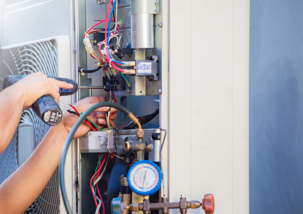 Male technician hands using a screwdriver fixing modern air conditioner, repairing and servicing, Maintenance and repairing concept