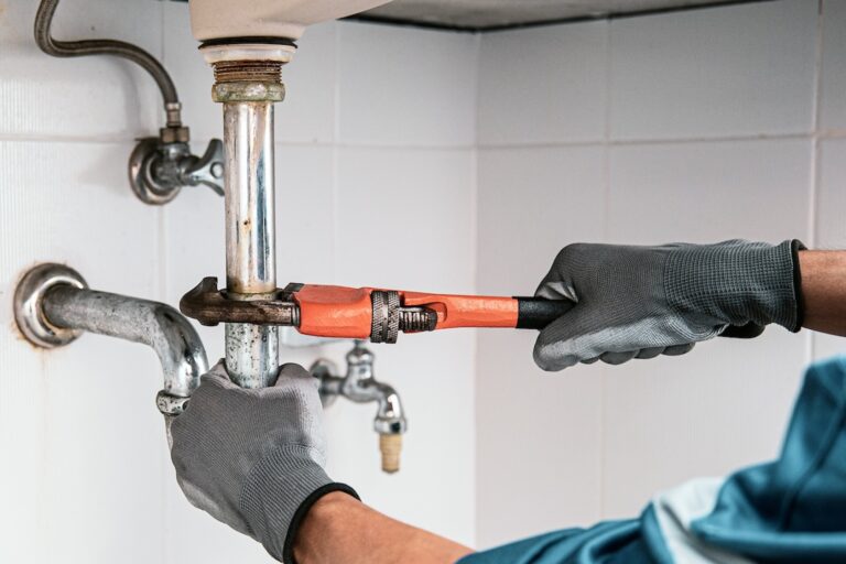 Technician plumber using a wrench to repair a water pipe under the sink. Concept of maintenance, fix water plumbing leaks, replace the kitchen sink drain, cleaning clogged pipes is dirty or rusty.