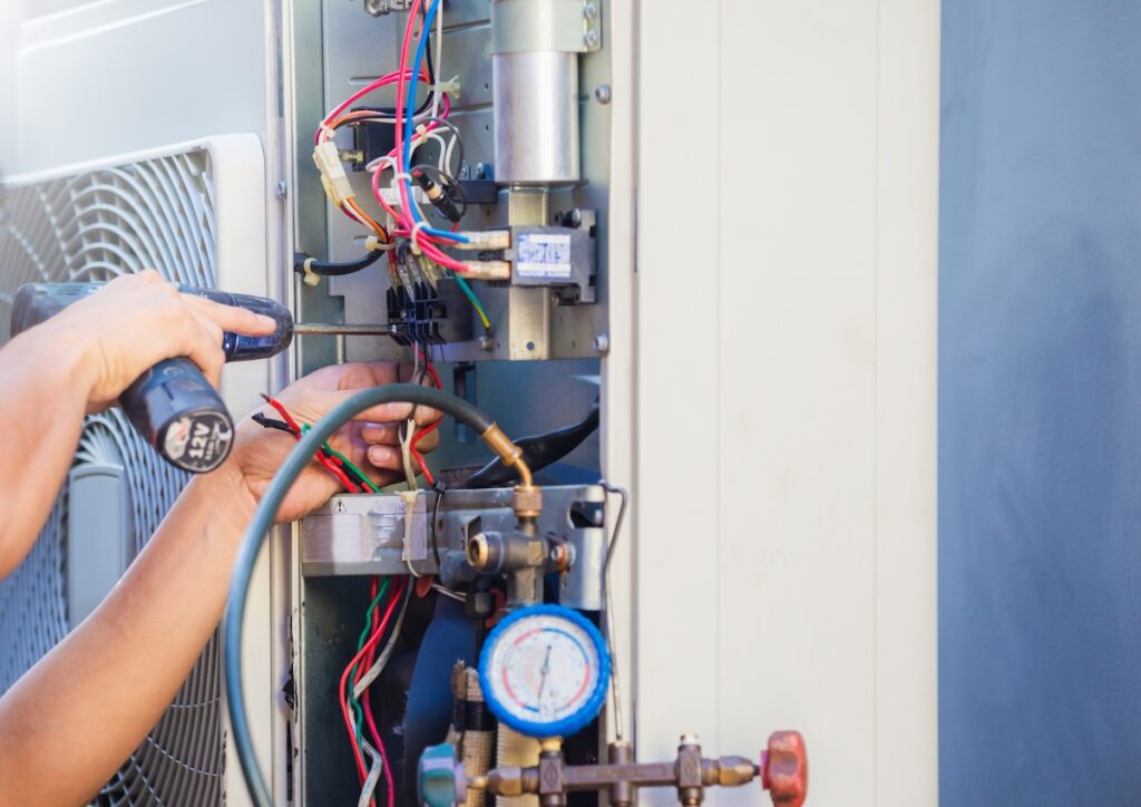 Male technician hands using a screwdriver fixing modern air conditioner, repairing and servicing,
