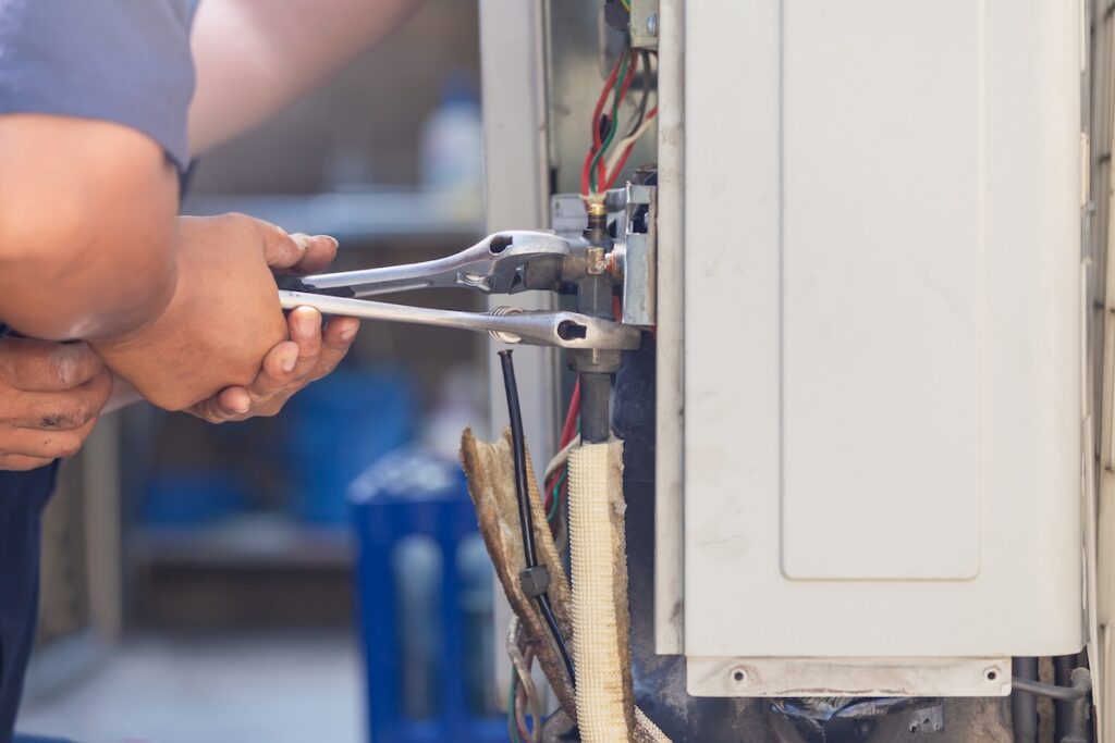 Technician man using a wrench fixing modern air system