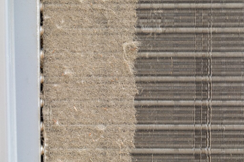 Dirty air conditioning unit. Condenser coil full of dirt and grass debris. Concept of home air conditioning, hvac, repair, service, cleaning and maintenance.