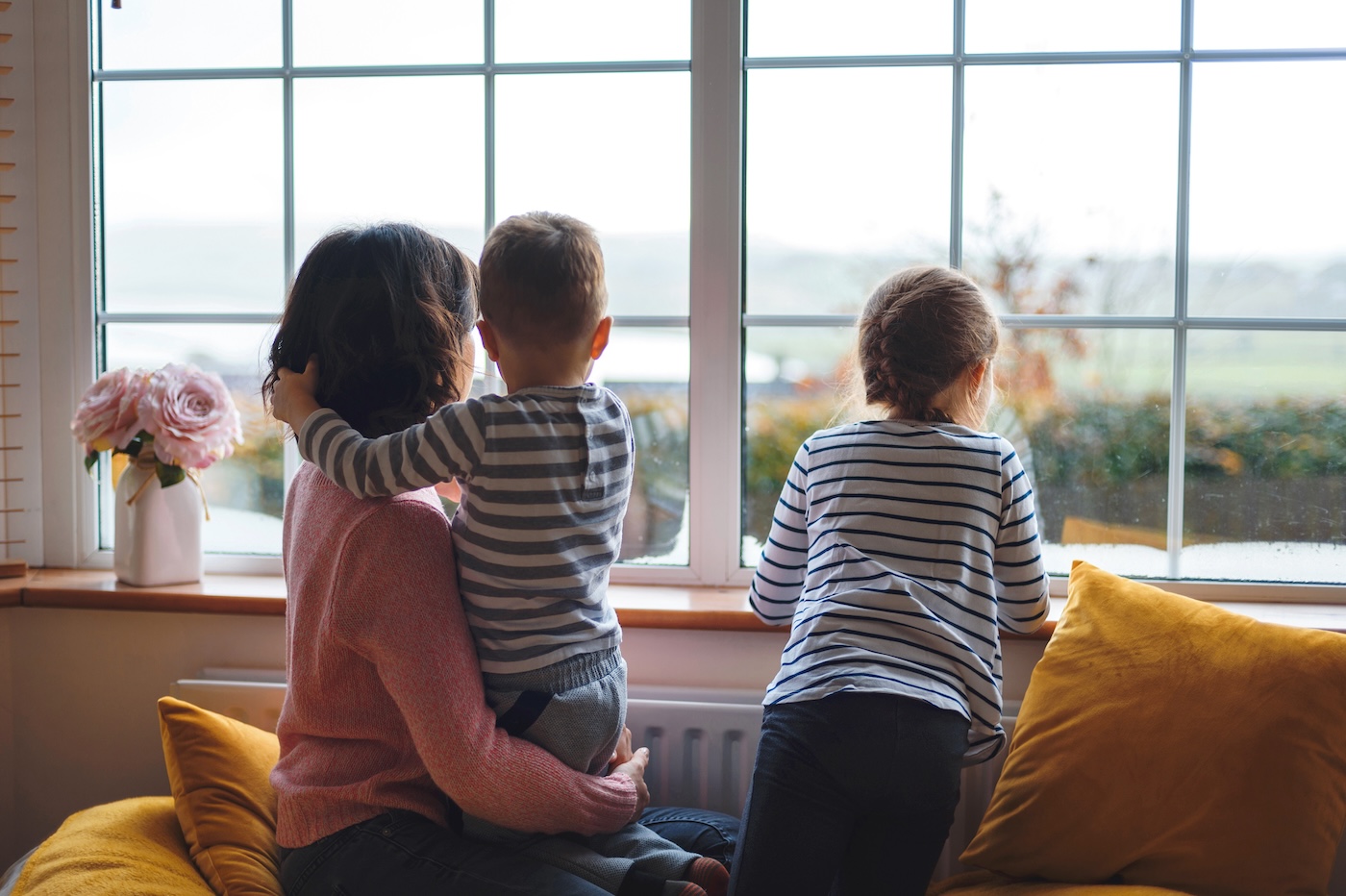 candid-family-looking-out-windows-of-home